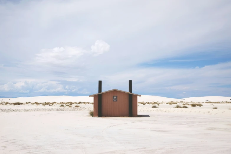 an outhouse sitting in the sand on a desert