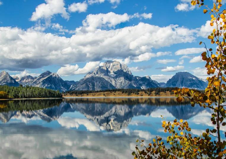 an almost calm lake sits below the grand tethered mountain range