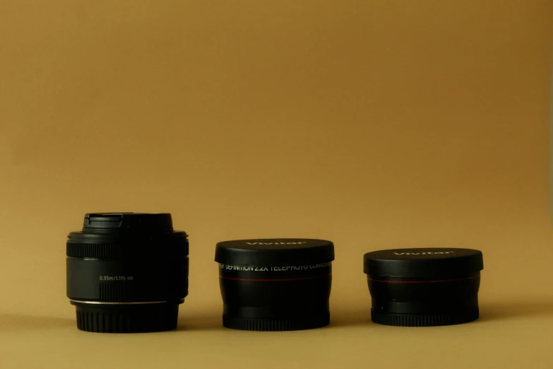 three camera lenses sitting on the ground next to a cup