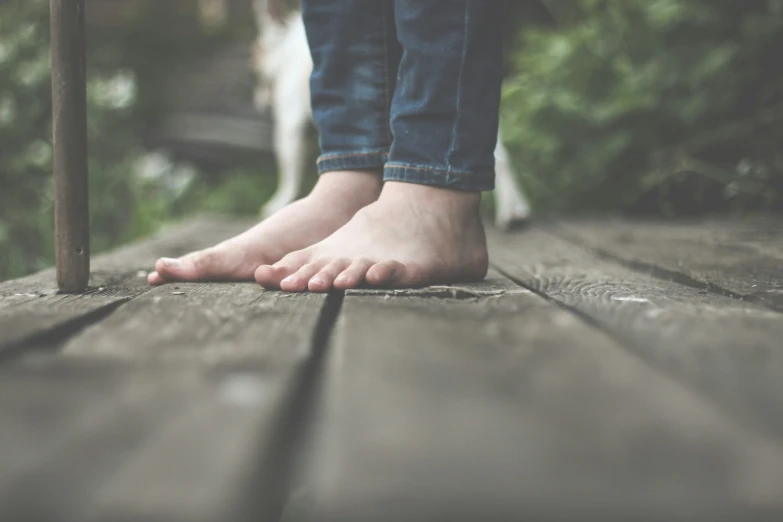 a person with bare feet standing on a wooden floor