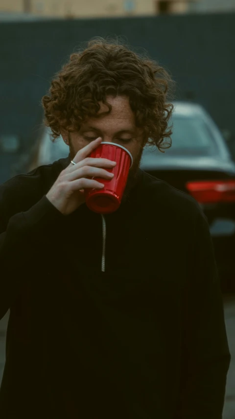a man in black sweater drinking from red cup