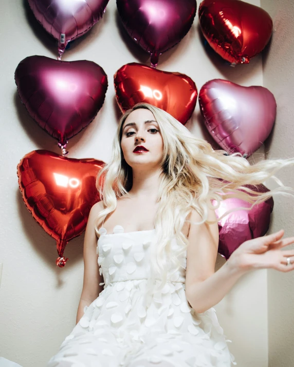 a woman in a white dress with many balloons around her