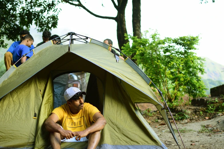 a person sits inside a green tent in the woods