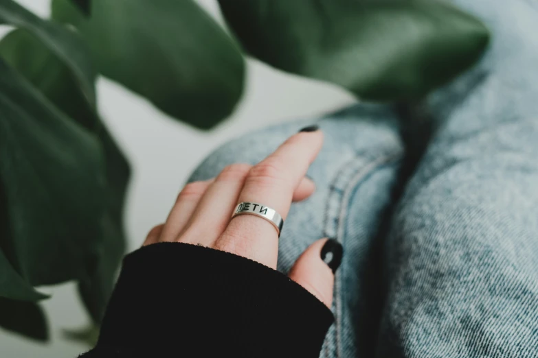 a woman wearing a ring is sitting near a plant