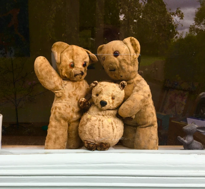 a group of three teddy bears sitting next to each other