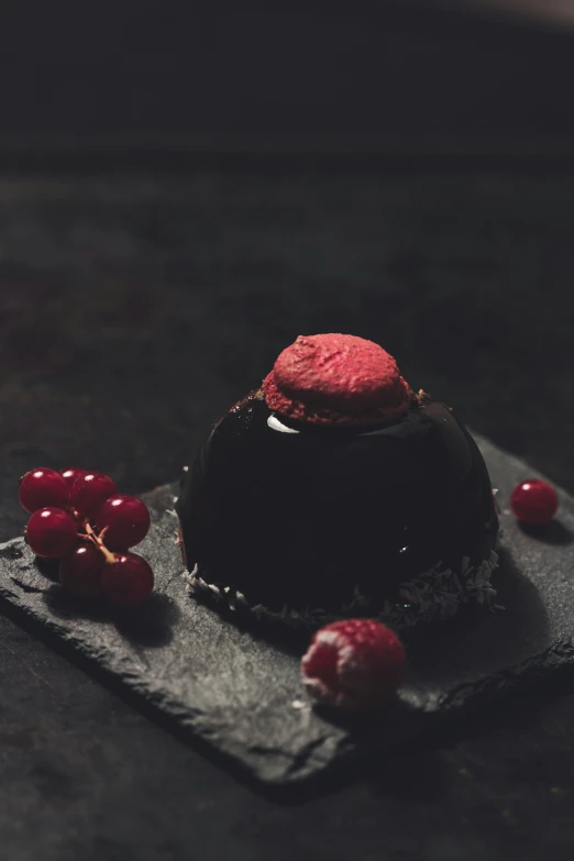 a dark chocolate dessert with a red garnish