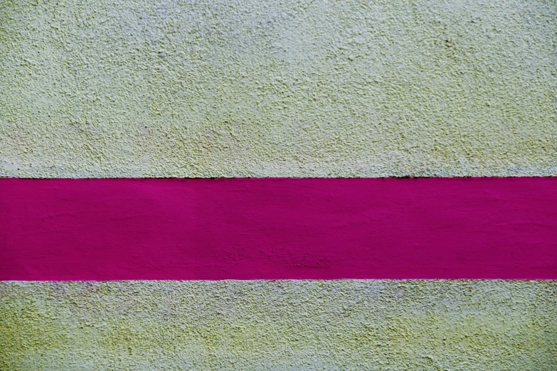 the wall is made of concrete with a pink strip