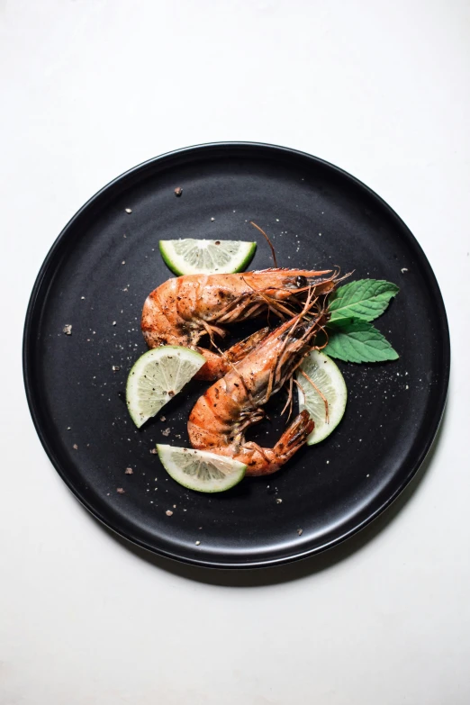 cooked shrimp on a plate topped with lemons and sage