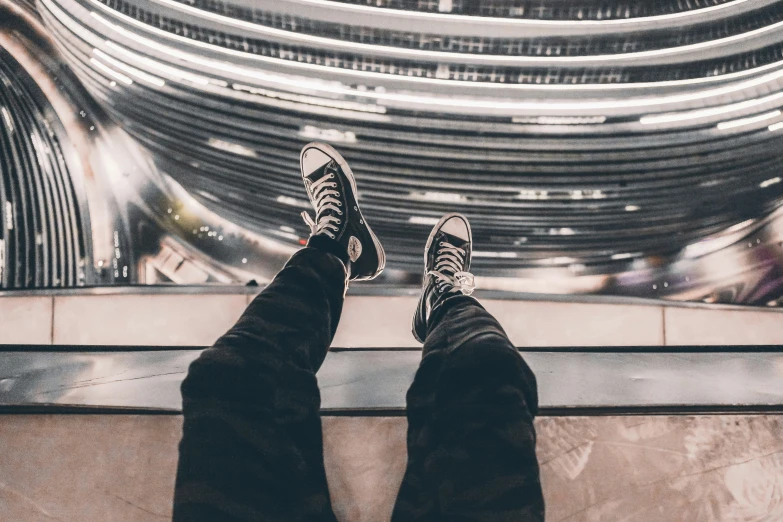 two legs with shoes on in front of a futuristic building