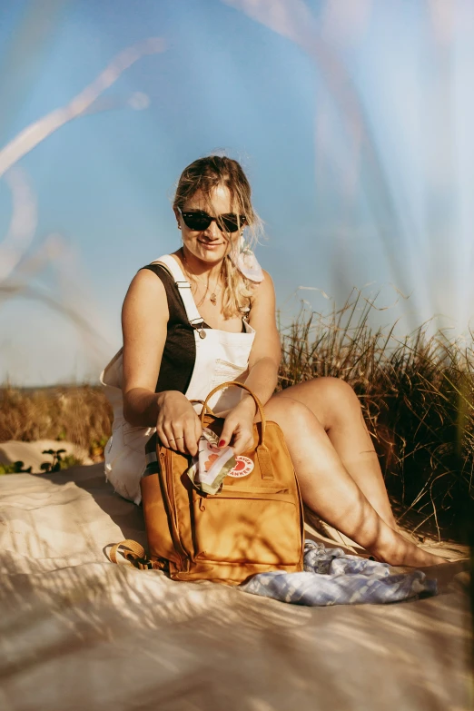 a woman holding a purse is sitting on a blanket