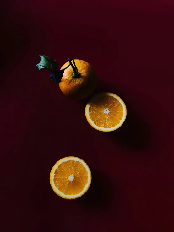 three whole oranges and two cut pieces laying on a table