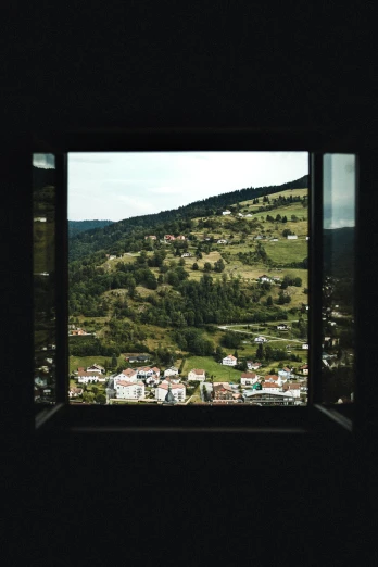 the view from outside a window shows hills and houses