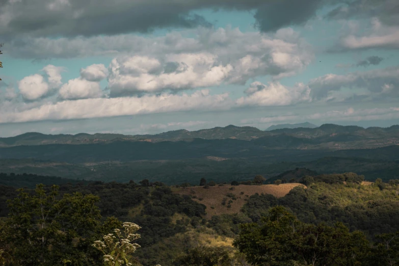 a tree covered valley is shown below some clouds