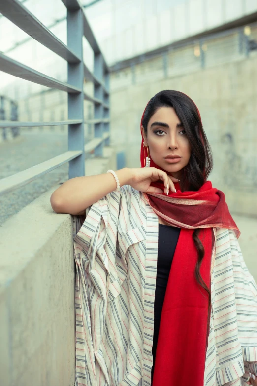 a woman wearing a red scarf leaning on the ledge of a building