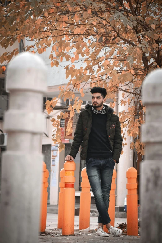 a man walking down a street near poles