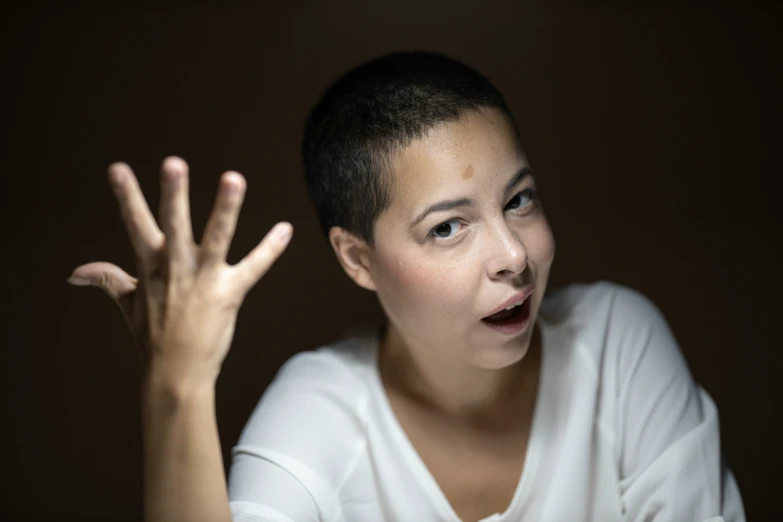 a woman in a white top is raising her hands with a shocked look