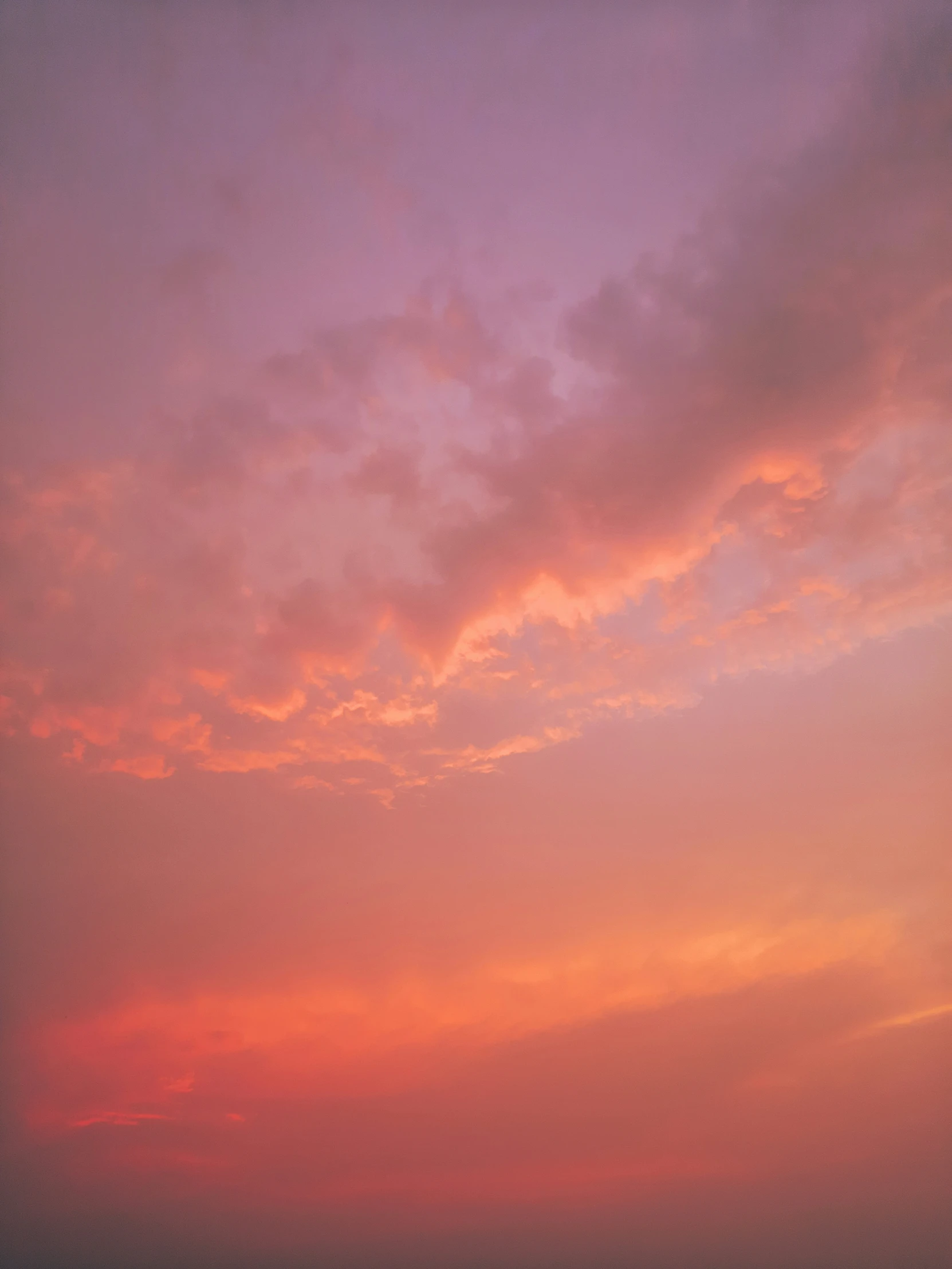 two people sitting on the beach with an umbrella watching the sunset