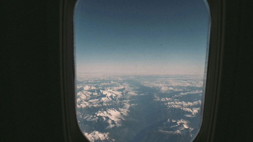 view from an airplane window shows snow covered mountains