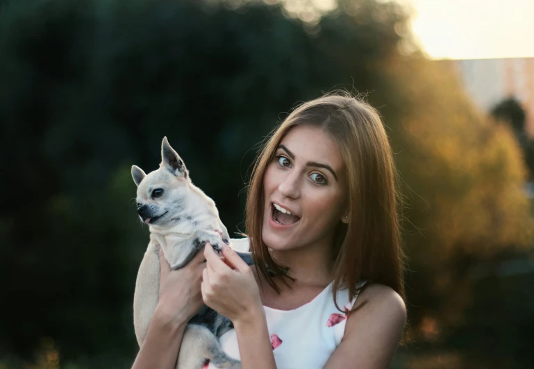 a woman holding up a dog in her hands