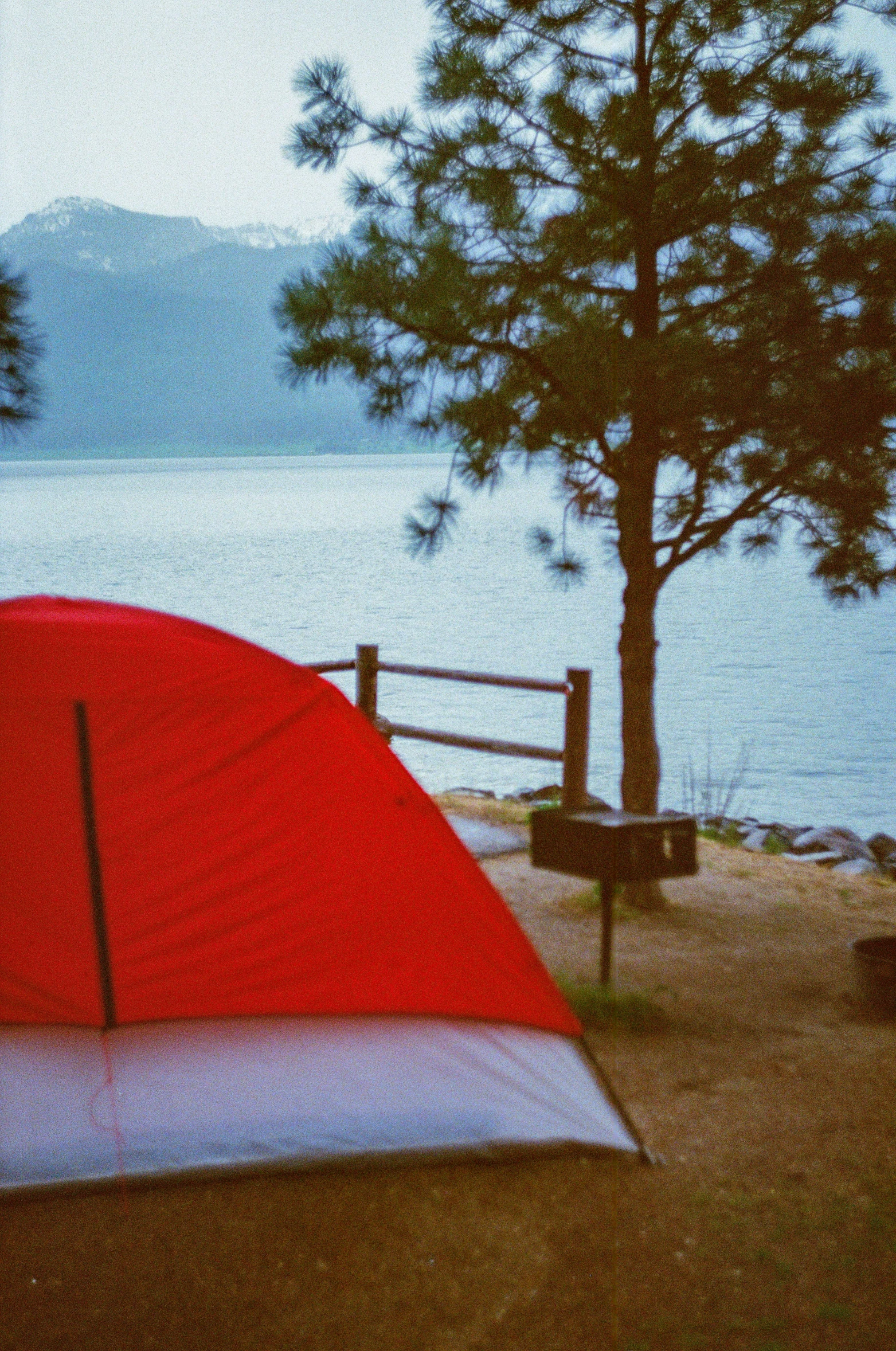 a red and white tent on grass by the water