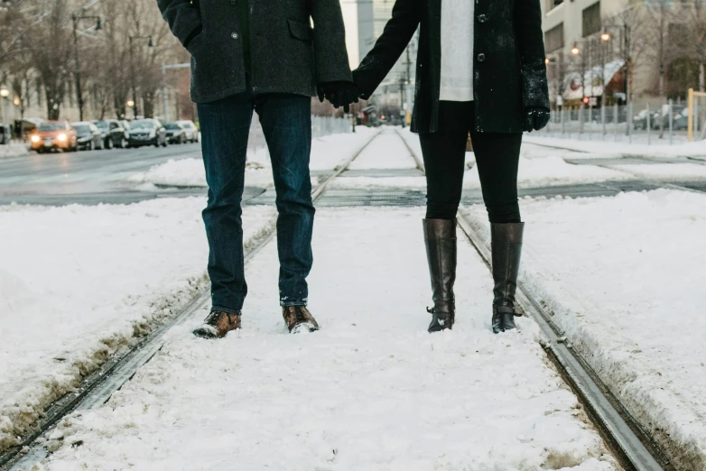two people holding hands walking through the snow