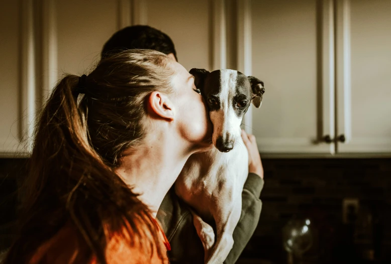 a woman kissing her dog in the kitchen