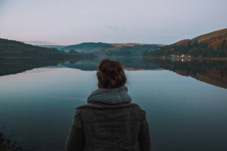 the woman is standing by the water alone