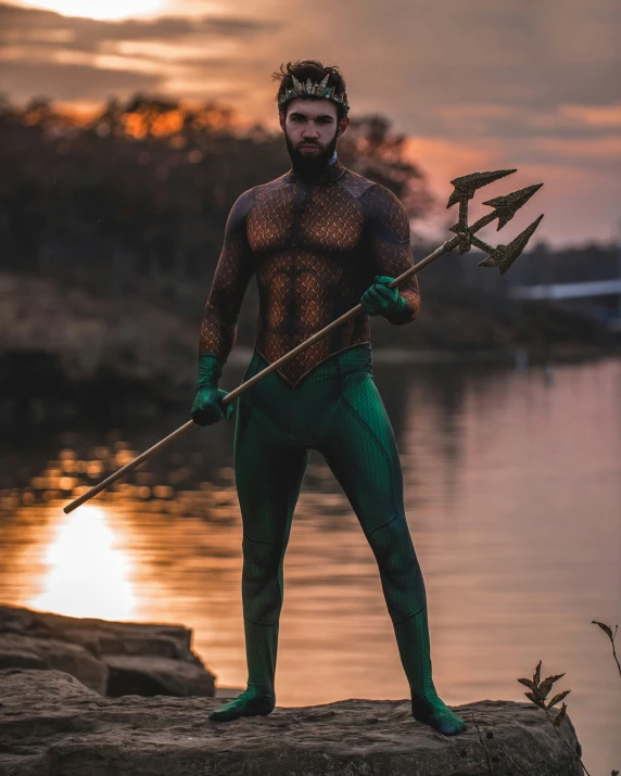 a person with makeup holding a spear next to the water