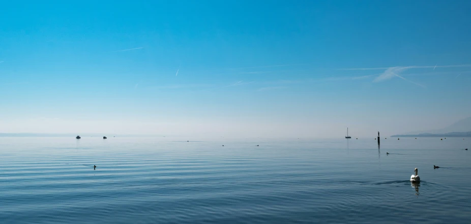 several boats in the ocean on a hazy day