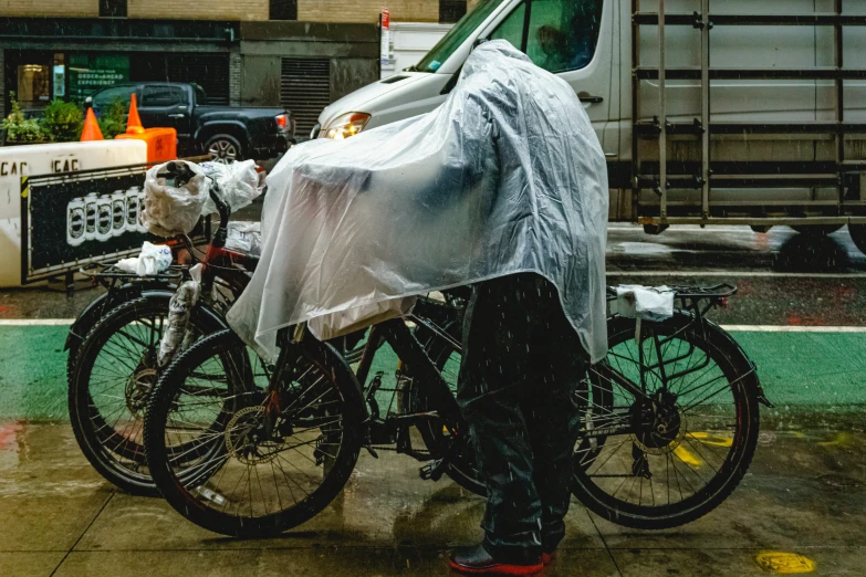 a man standing next to two bikes covered in plastic