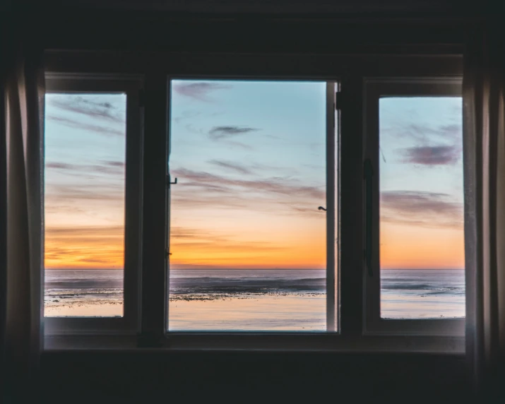 a window view out to the ocean at sunset