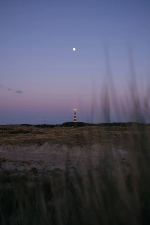 lighthouse with the full moon in the distance