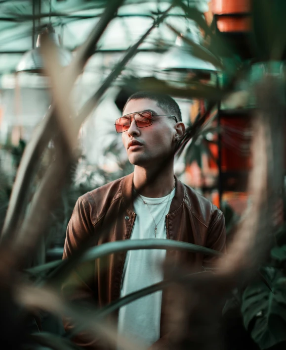 a man is standing in a greenhouse with glasses on