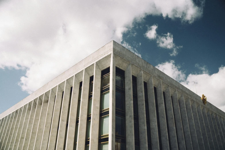 the top of a building with tall columns against a cloudy sky