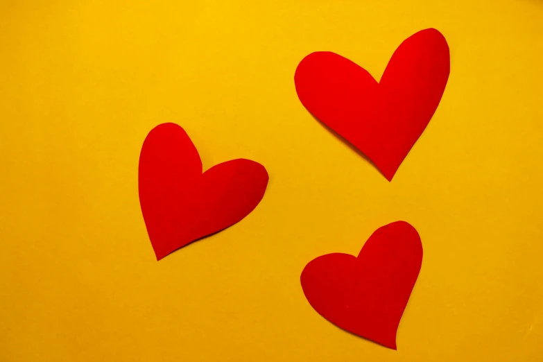 three red hearts sitting on top of a yellow table