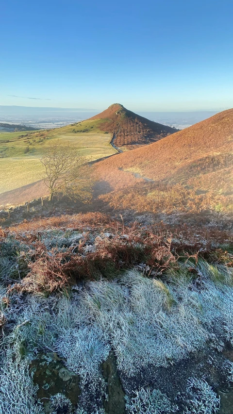 a po taken at the top of a mountain shows a blue sky and grassy area with an open field