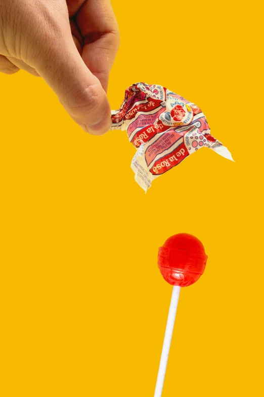a hand holding a candy bar and lollipop