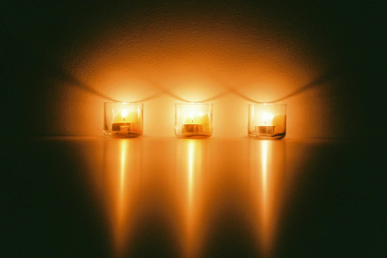 three small jars with candle light and water