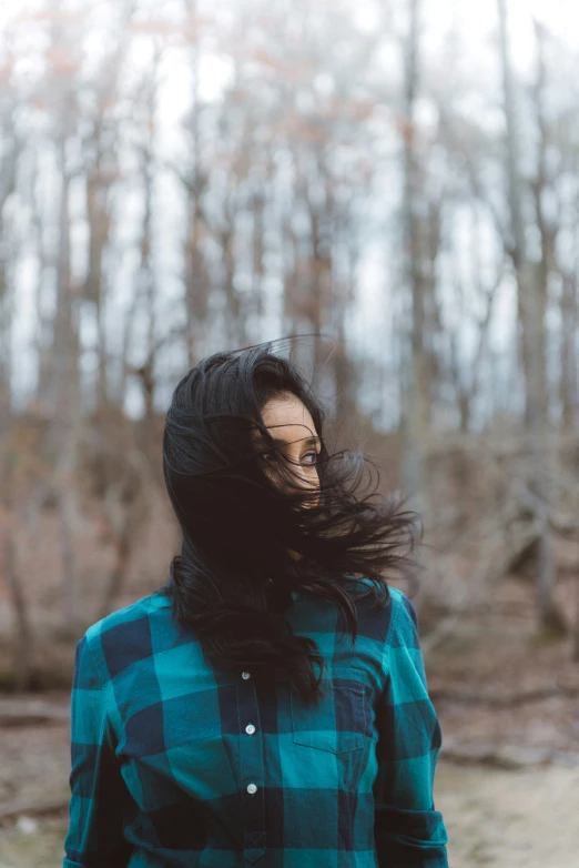 a woman with her hair blown up wearing a green and black jacket