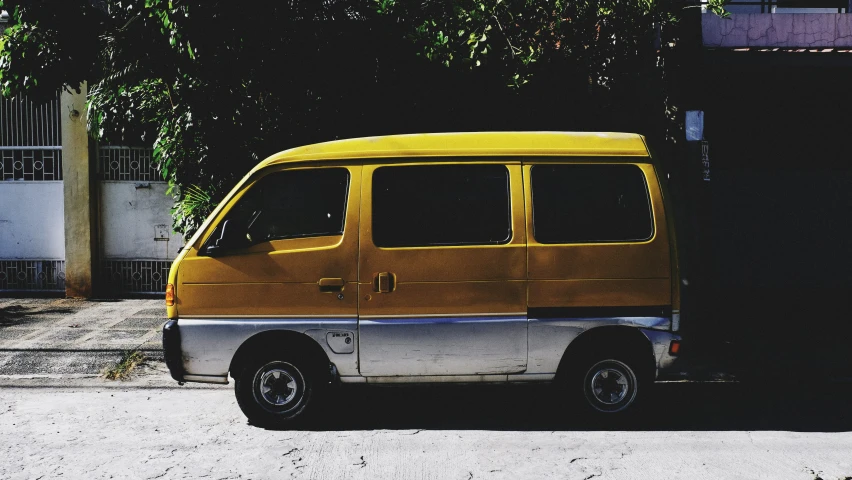 a yellow van parked next to a building with trees