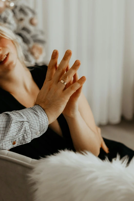 a blonde woman sitting on a white couch with her hand in her mouth