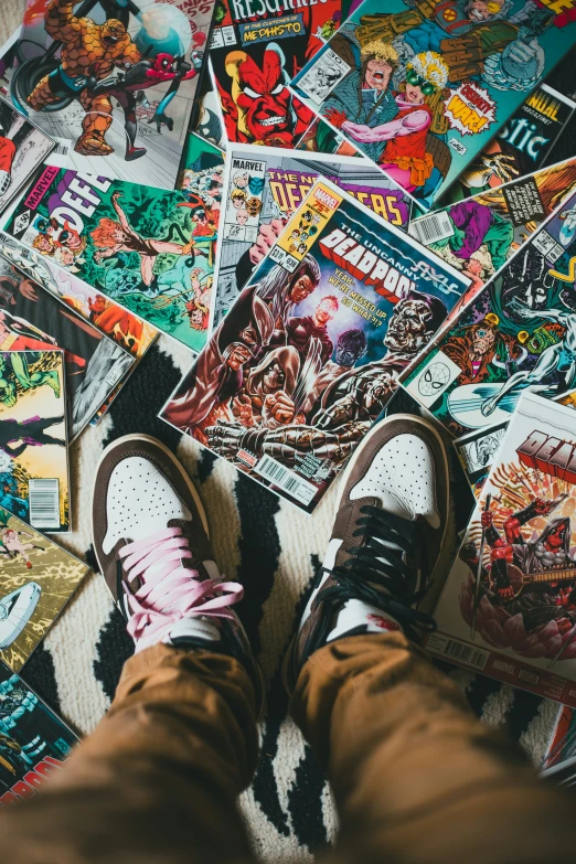 a person's feet in sneakers are surrounded by comic covers