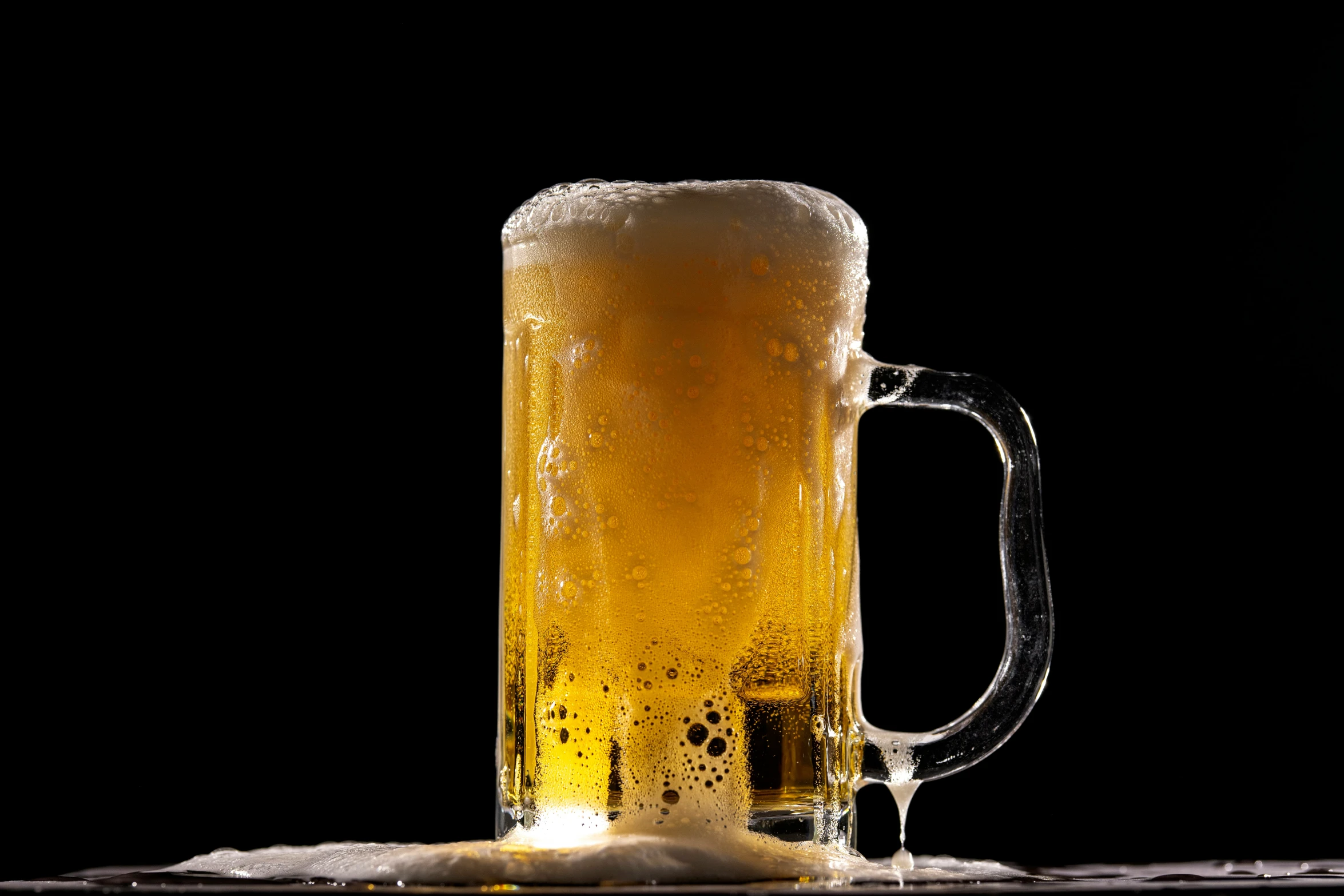 a beer mug sits on a table against a black background