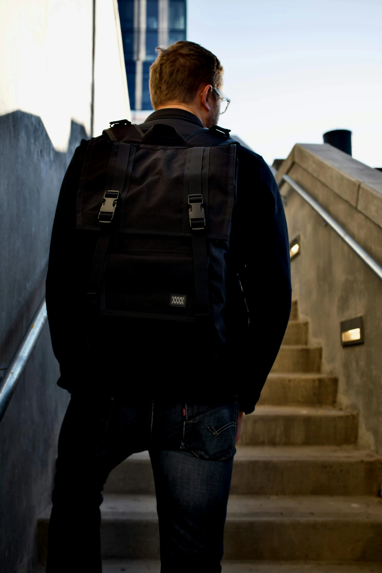 a man in black jacket and jeans walking up stairs