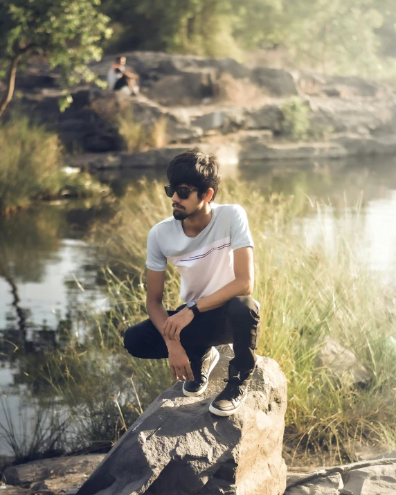 a man sitting on top of a rock next to water