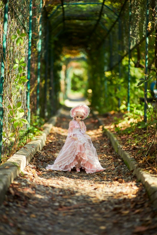 a woman in a long, pink dress stands alone in the middle of a garden