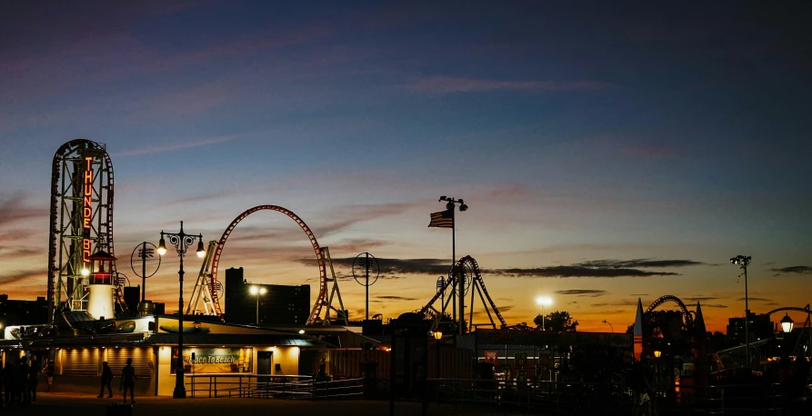 the rides in an amut park with the sun setting in the background