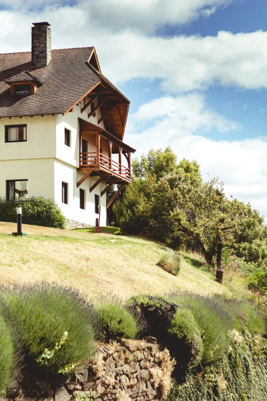 a white house in the mountains sits on top of a hill