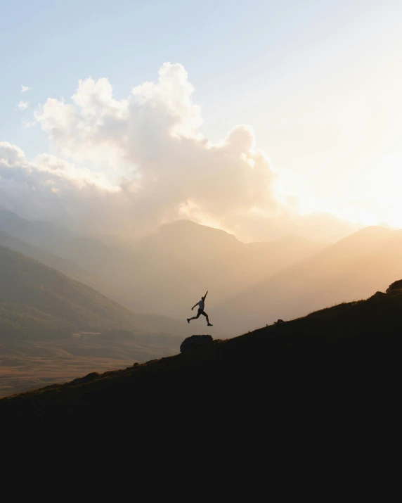 a man running along side a hill during sunset