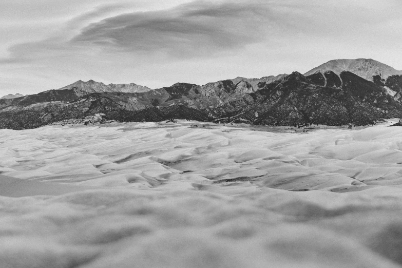 an airplane flies over snow covered mountains on a cloudy day